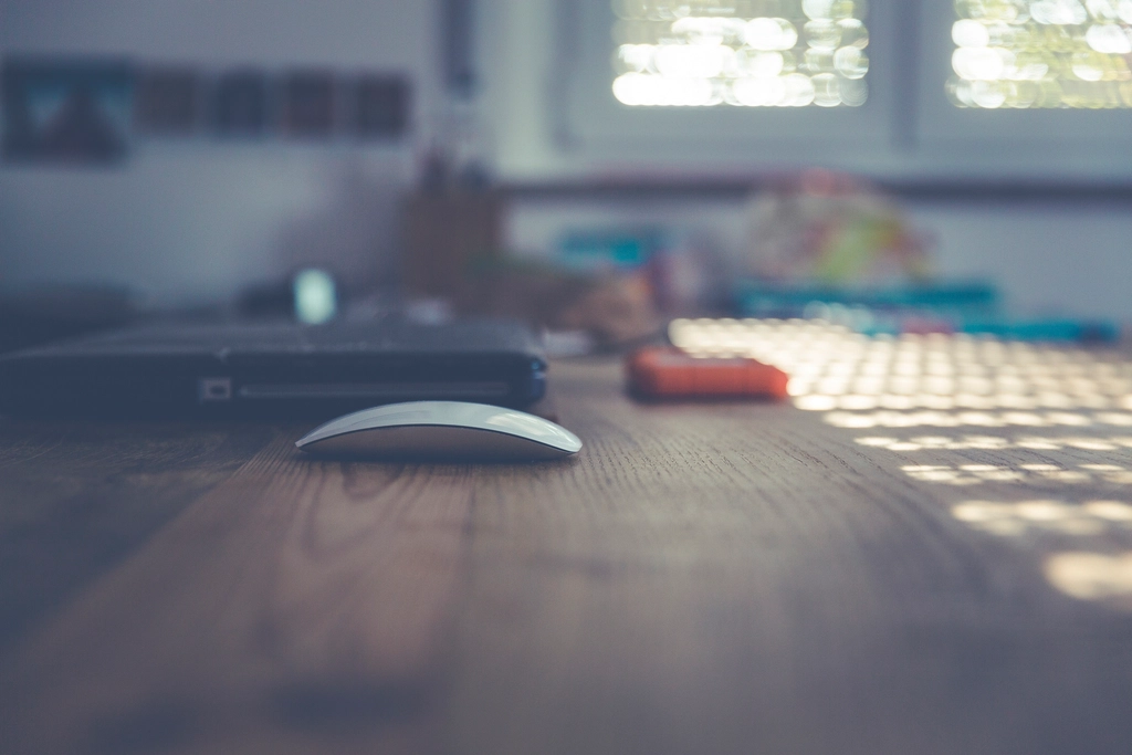 A modern laptop with a hardware security key plugged in on a wooden workspace desk.