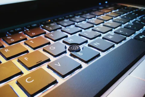 A modern laptop on a clean wooden desk representing AI assistant software.