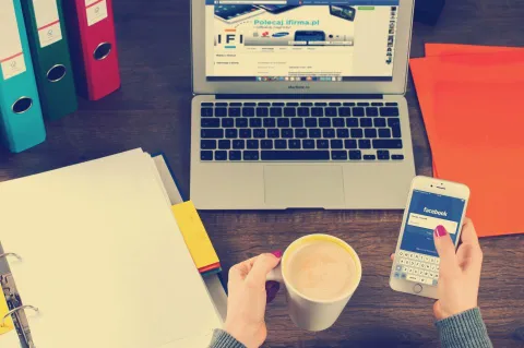 حاسوب محمول وهاتف ذكي على مكتب يعبران عن إدارة وأمان الحسابات الرقمية