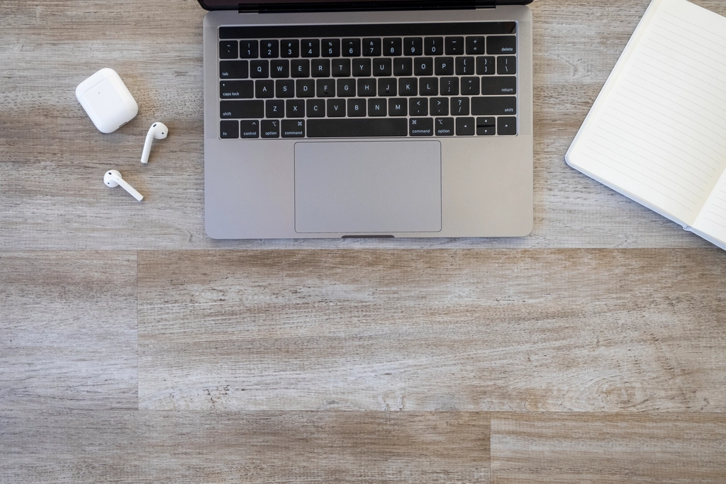 AirPods and an iPhone showing the FaceTime app interface on a wooden desk.
