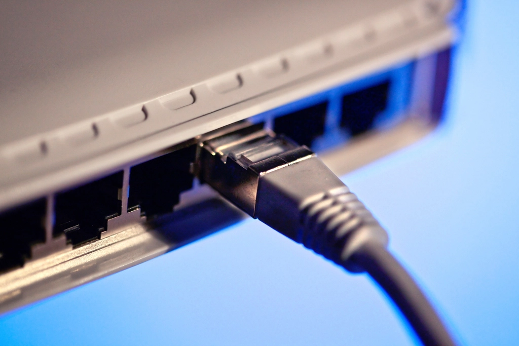 A modern Spectrum modem connected to a personal Wi-Fi router with an Ethernet cable.