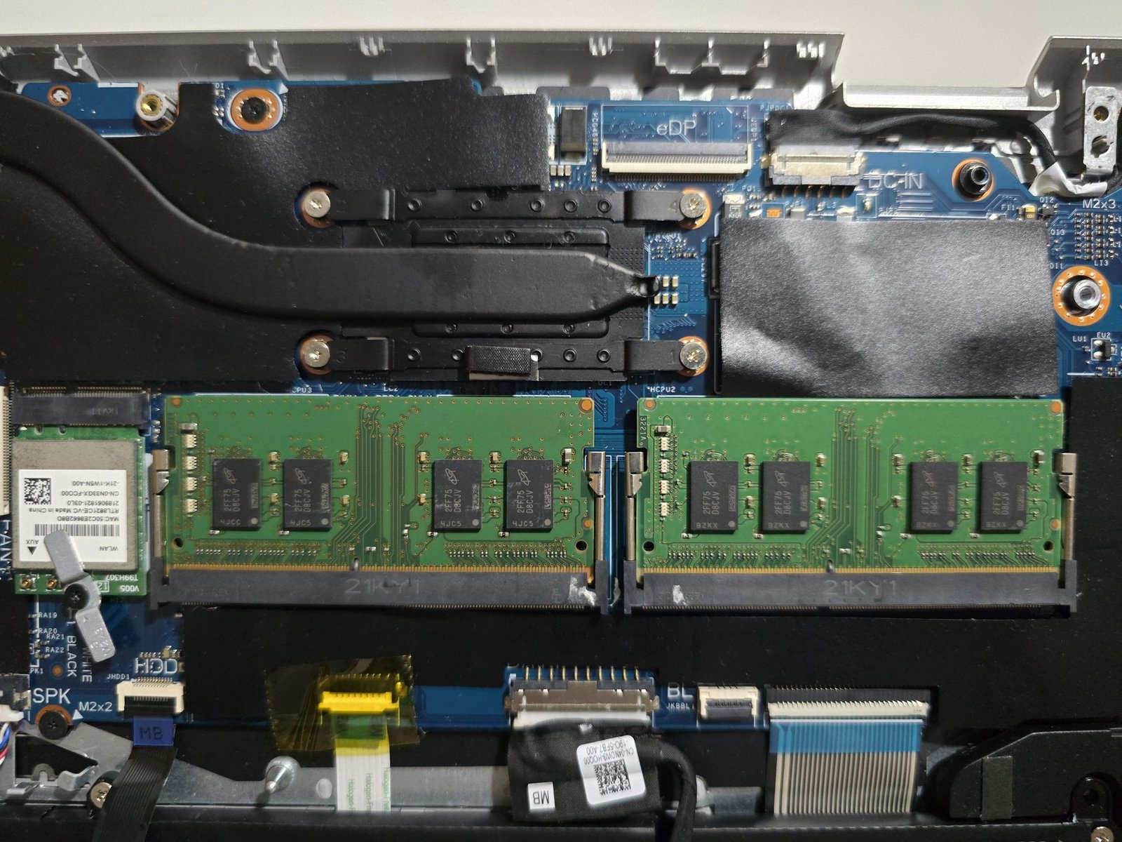 A modern laptop on a wooden desk showing side ventilation ports.