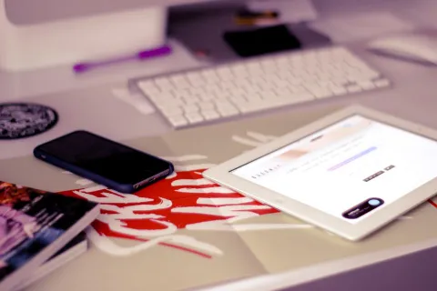 An iPad tablet resting on a wooden desk alongside a stylus pen.