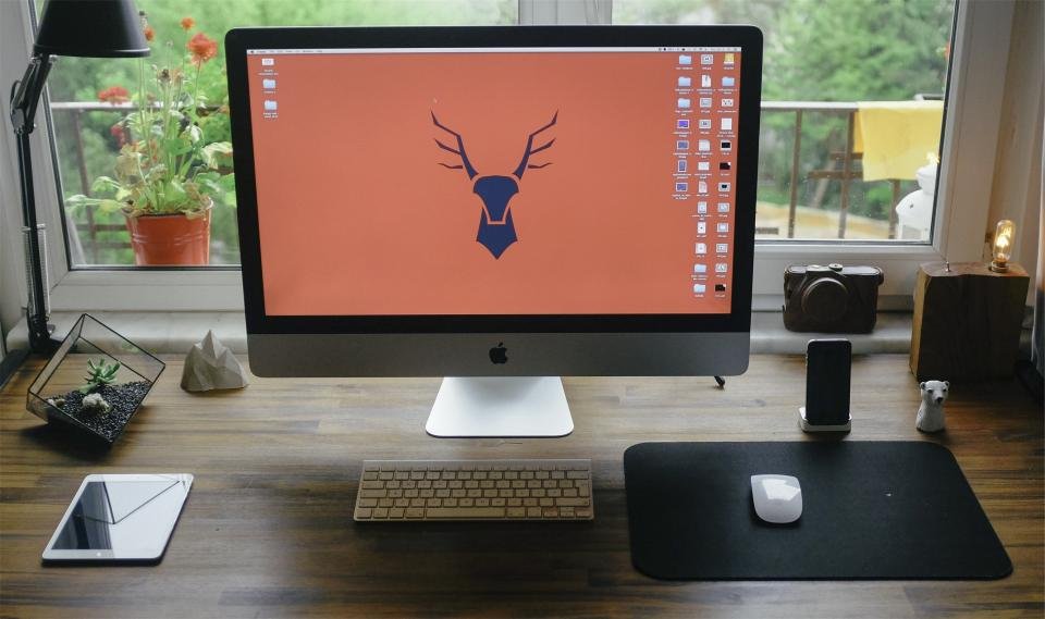 Desktop computer monitor displaying a black screen next to a keyboard and mouse on a modern workspace desk.