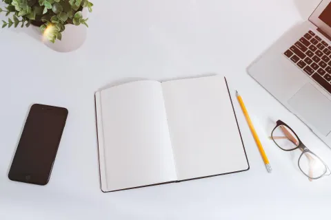 باحث يقرأ ويلخص أوراقاً علمية باستخدام لابتوب على مكتب دراسي منظم
