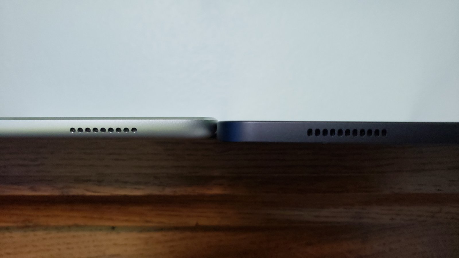 A Samsung Galaxy smartphone sitting on a wooden desk next to a phone case.