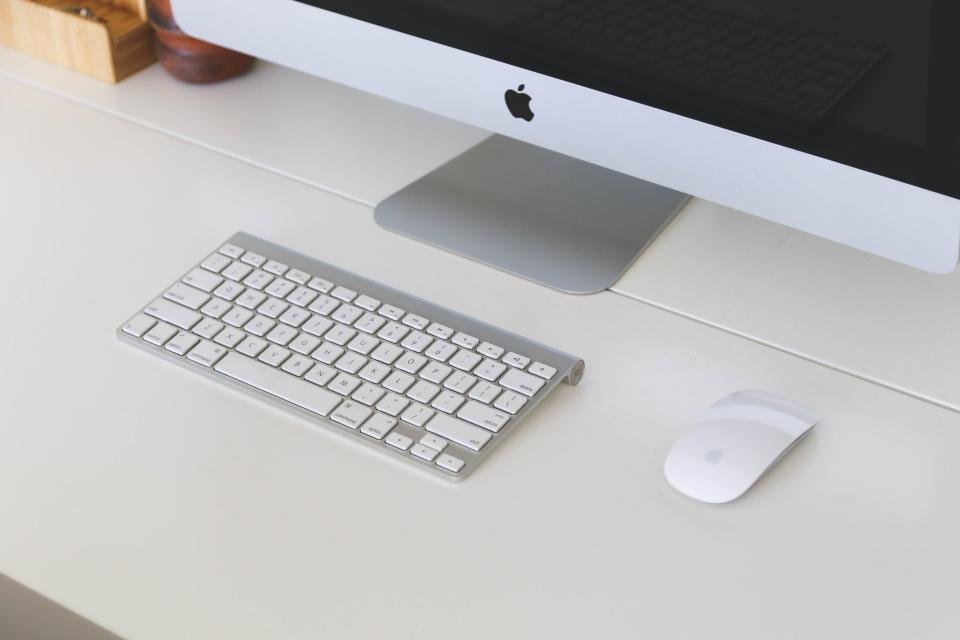 A computer keyboard and monitor set up on a clean desk workspace.